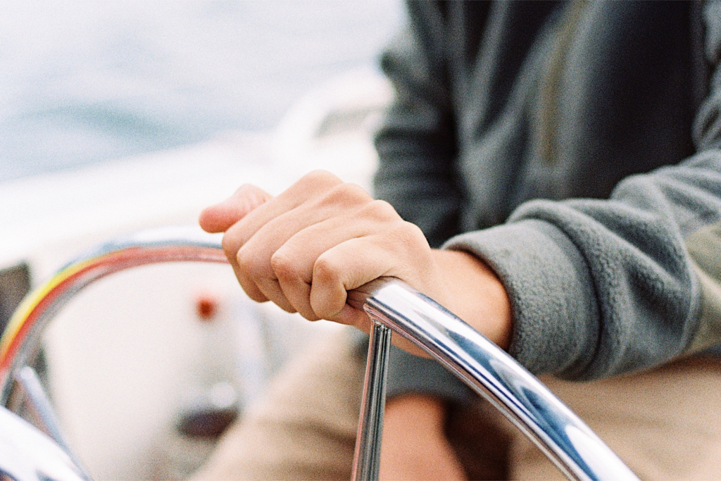 Person steering a boat during a day at sea