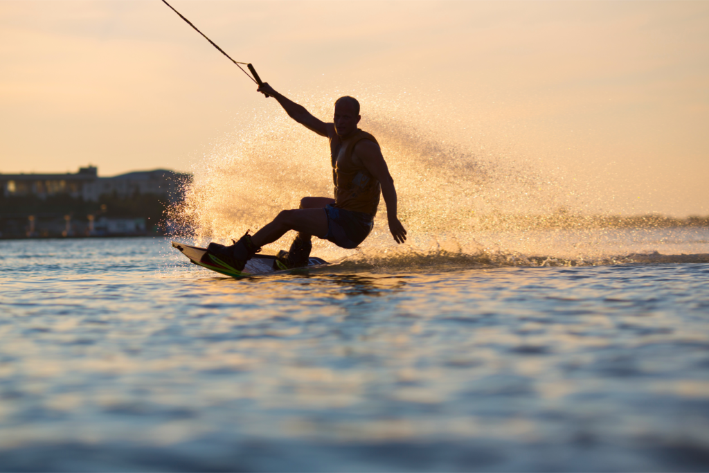 Person wakeboarding behind a boat at sunset