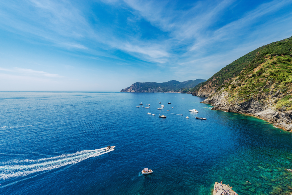 Panoramic view of a bay surrounded by cliffs with several boats cruising offshore